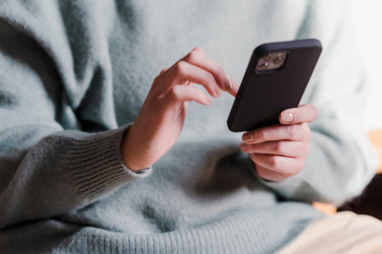 A photo of a person sat down, on a mobile phone