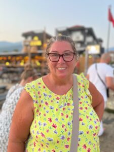 Jan, wearing a yellow top, smiles at the camera