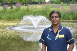 Sumitha in her blue nurse uniform with a waterfall in the background