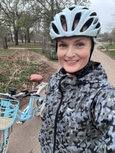 Kristina smiling into the camera with her bike and wearing a cycling helmet