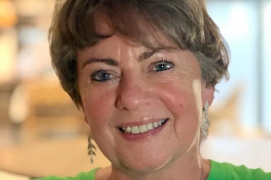 Jacqueline Totterdell wears a green top and smiles into the camera