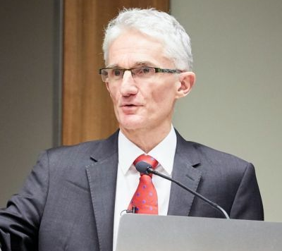 Sir Mark Lowcock in a grey suit, white shirt and red tie