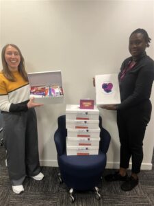 Two women standing up with a pile of the boxes
