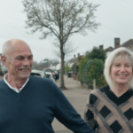 Paul and Dawn Curtis, holding hands, walking down the road. They both have a smile on their faces.