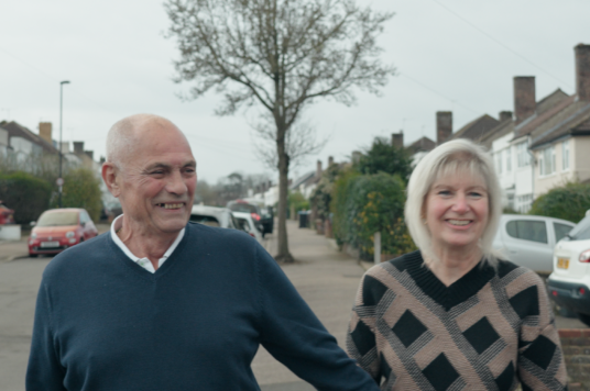 Paul and Dawn Curtis, holding hands, walking down the road. They both have a smile on their faces.