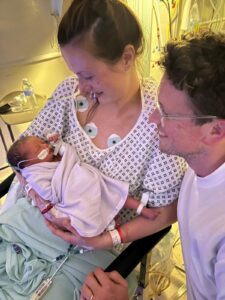 Harriet holds her baby as her husband looks on